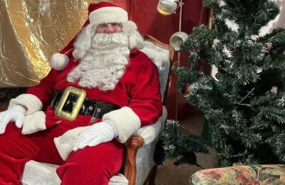 Père Noël assis dans un fauteuil confortable près de son sapin