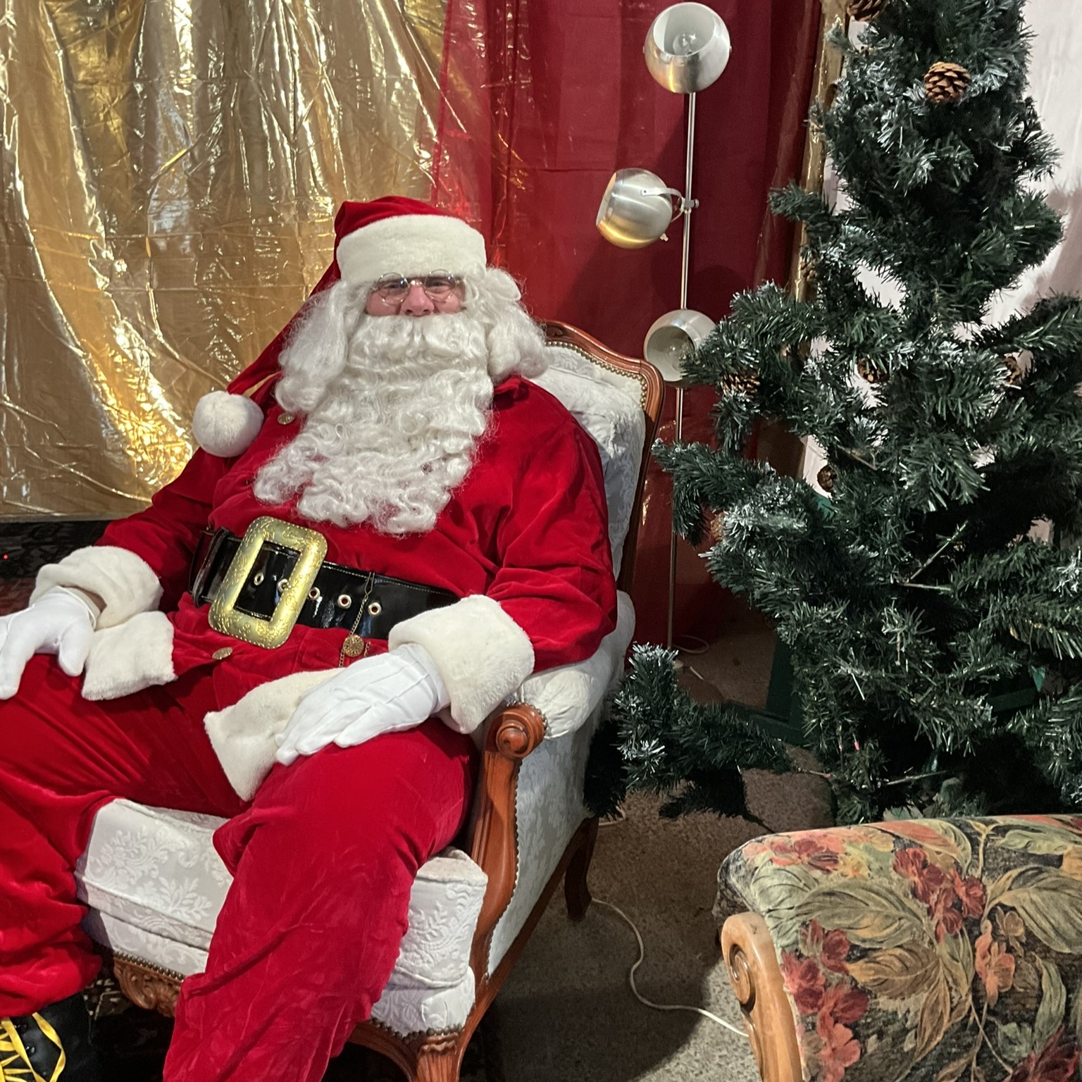 Père Noël assis dans un fauteuil confortable près de son sapin